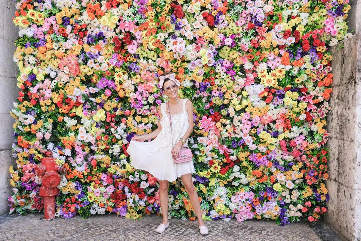 Woman in white dress in front of colorful flower wall - The Village Florist Hunters Hill