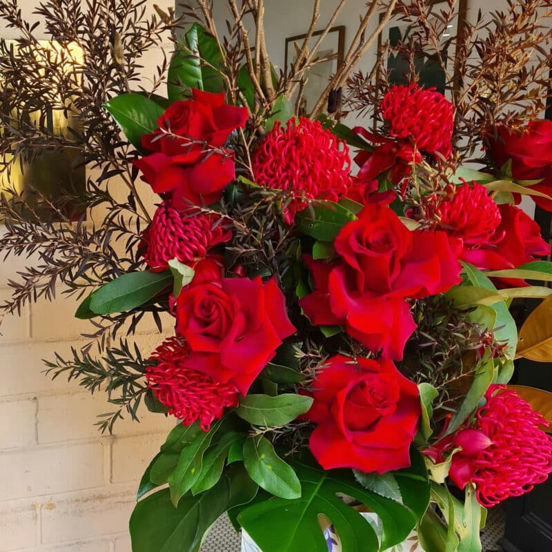 Vibrant red roses and native Australian flowers in a classic arrangement. - The Village Florist Hunters Hill