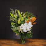 White orchids, lilies, and magnolia leaves in a glass vase. - The Village Florist Hunters Hill
