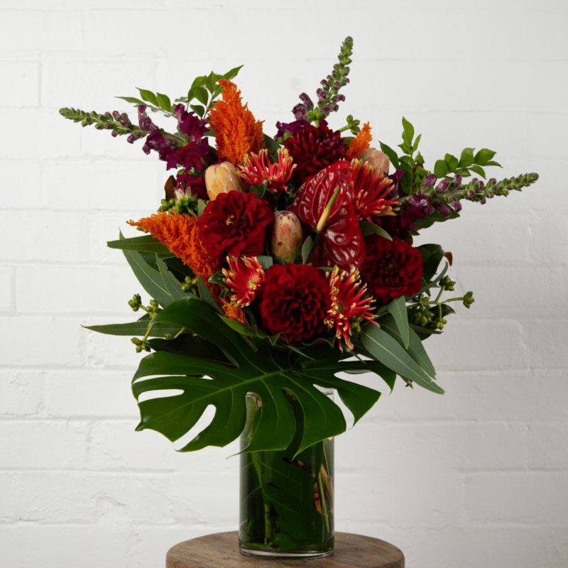 Red and orange floral arrangement with monstera - The Village Florist Hunters Hill
